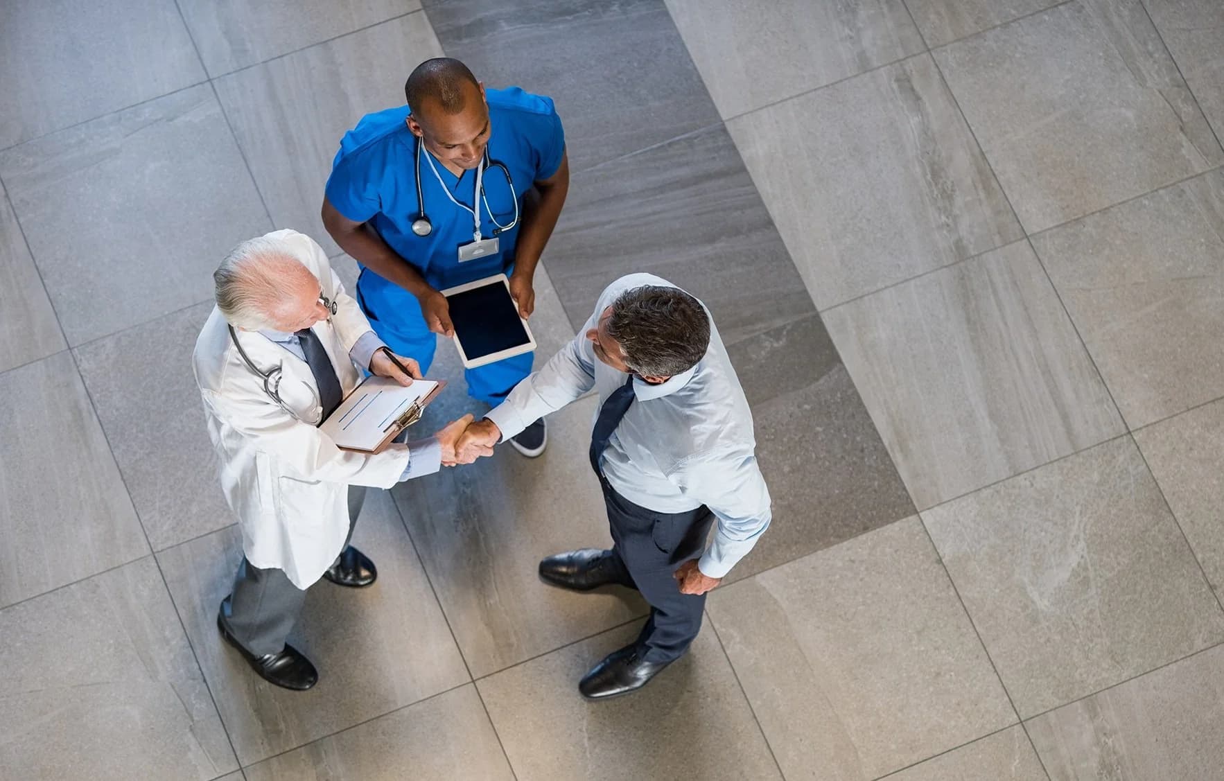 Healthcare professionals shaking hands in a hospital atrium